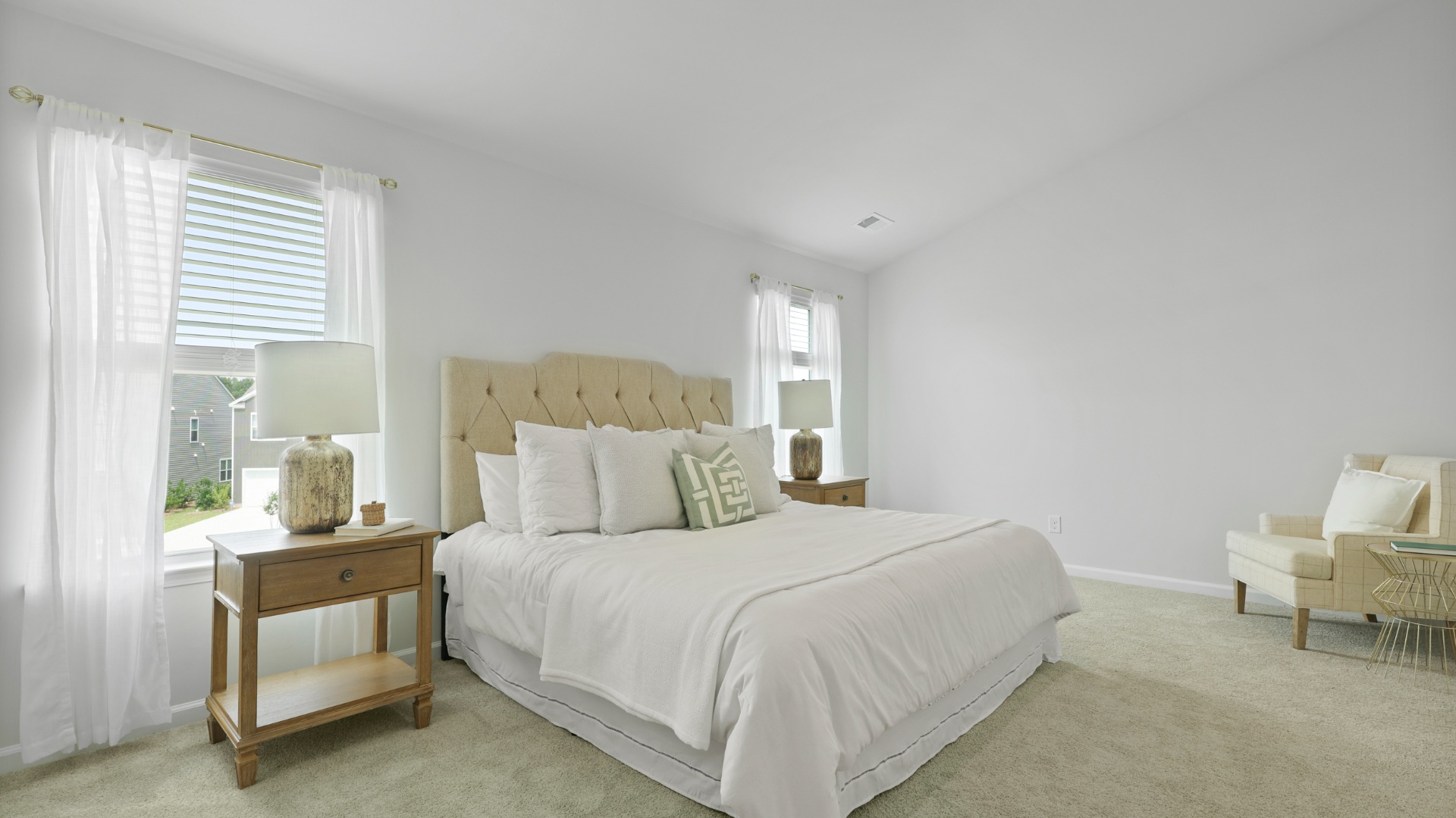 Primary bedroom decorated with a bed, side table and a sitting area