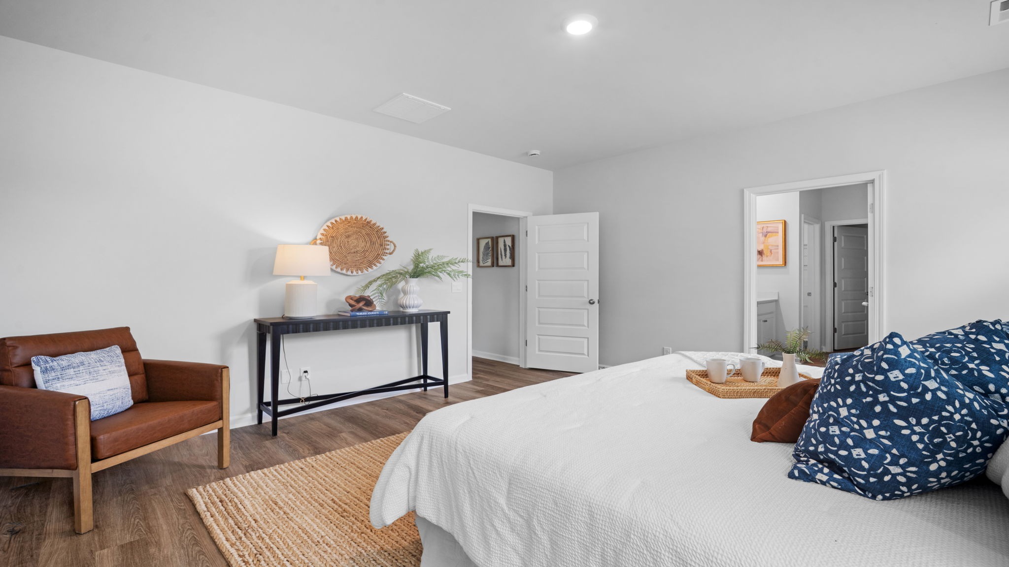 Primary bedroom decorated with a bed, bench, side table and a chair