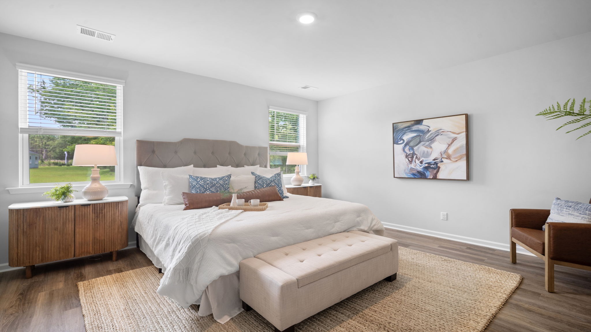 Primary bedroom decorated with a bed, bench, side table and a chair
