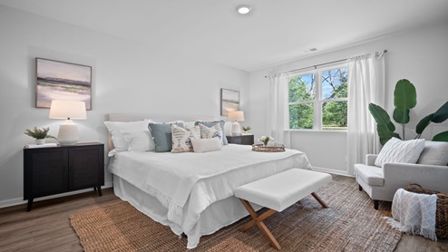 Primary bedroom decorated with a bed and side table