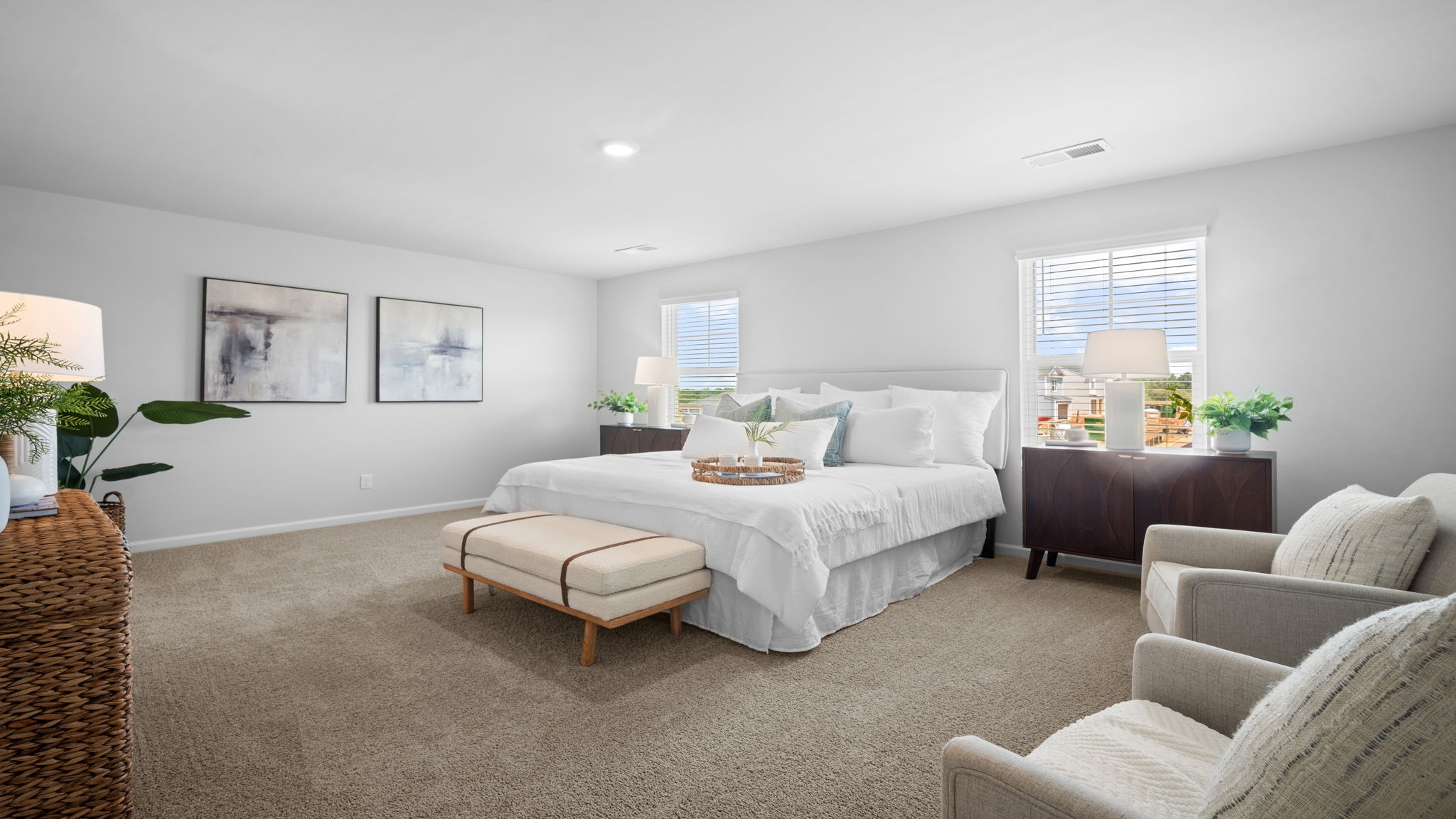 Primary bedroom decorated  with a bed, bench, side table and chair