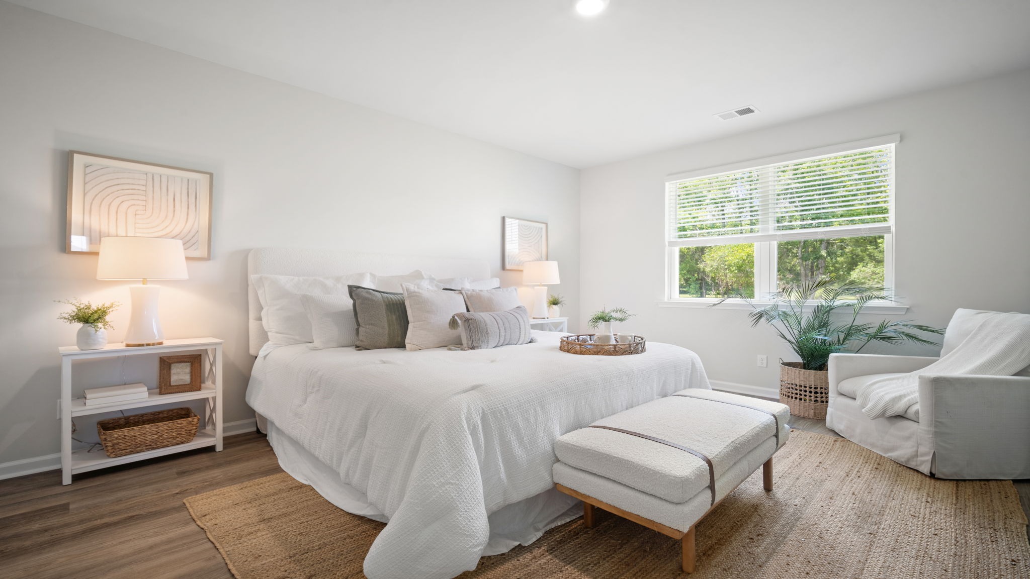 Primary bedroom decorated with a bed , bench, side table and a chair