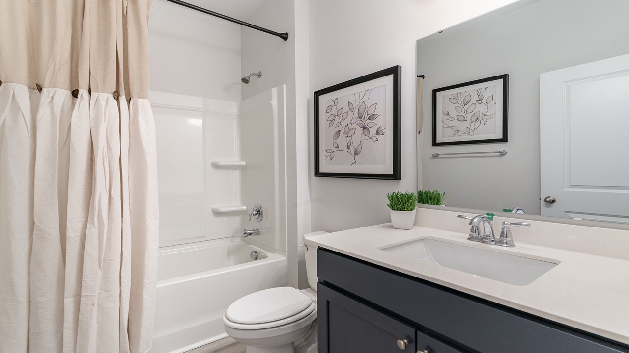 secondary bathroom with gray cabinets and a shower tub combo