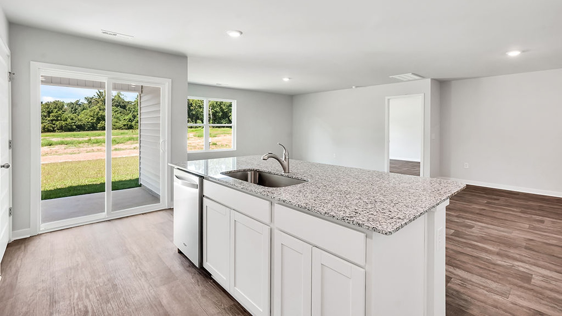 The open-concept family room, kitchen, and dining area feature granite countertops, stainless steel appliances, including a smooth-top range, dishwasher, and overhead microwave.