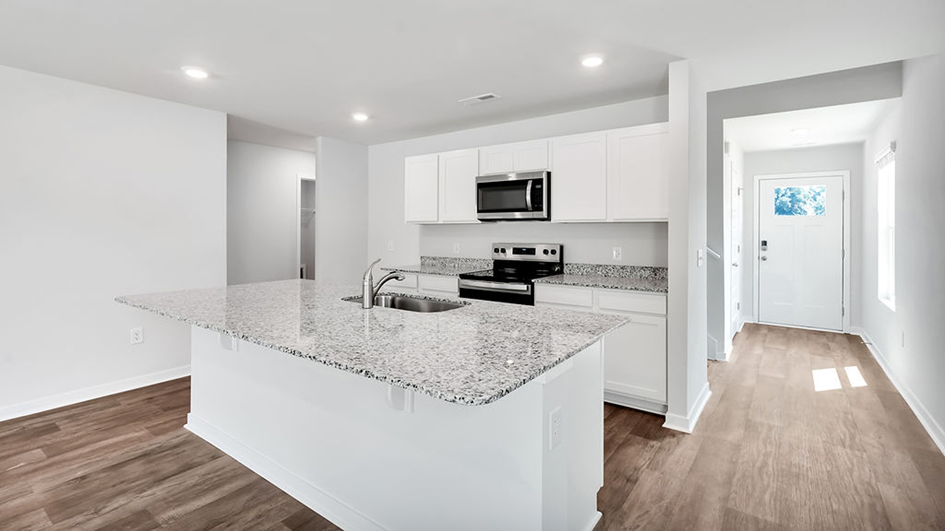 This beautiful kitchen features white cabinetry, granite counters, a large kitchen island