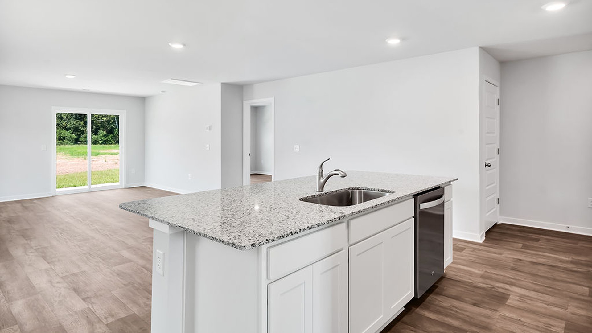 This beautiful kitchen features white cabinetry, granite counters, a large kitchen island