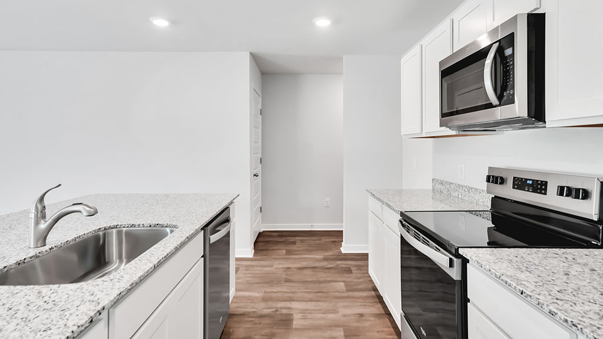 This beautiful kitchen features white cabinetry, granite counters, a large kitchen island