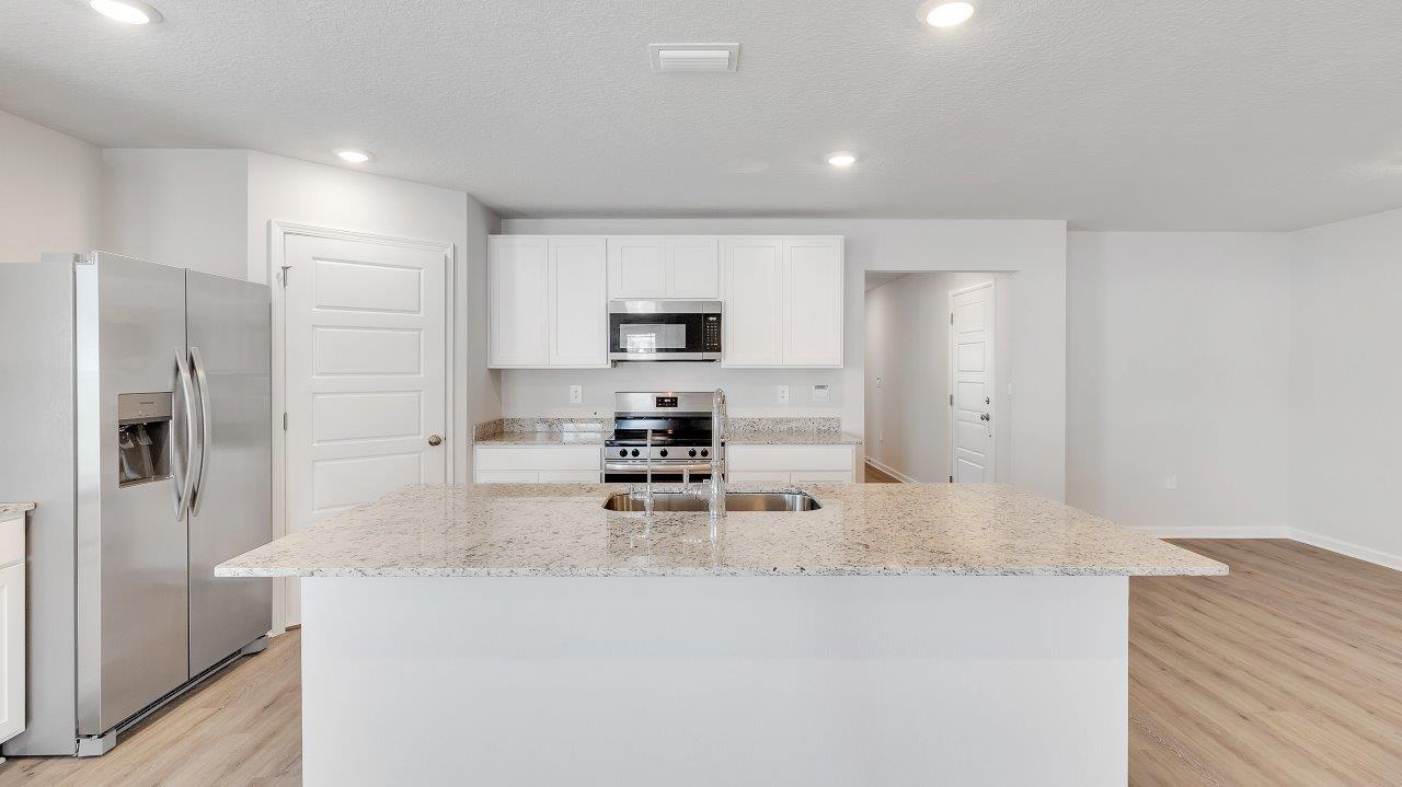The kitchen boasts a stunning design featuring granite countertops, spacious island bar, stainless-steel appliances and a corner pantry.