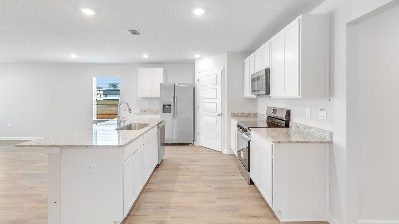 The kitchen boasts a stunning design featuring granite countertops, spacious island bar, stainless-steel appliances and a corner pantry.