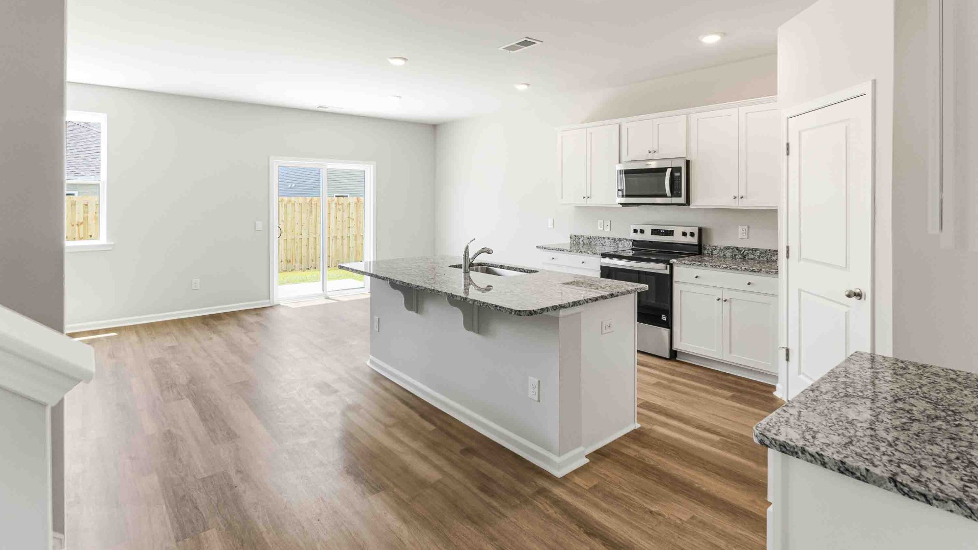 The open-concept kitchen features granite countertops and stainless-steel appliances. The large island is great for gatherings. The kitchen seamlessly connects to the dining and living areas, creating a great space for entertainment.