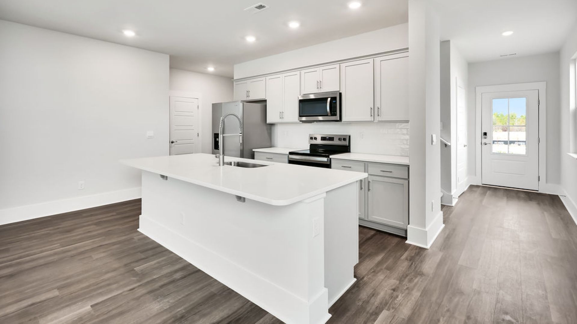 The heart of the home is its open concept kitchen with granite counters, stainless-steel appliances, and a generous island flowing into the dining and living areas.