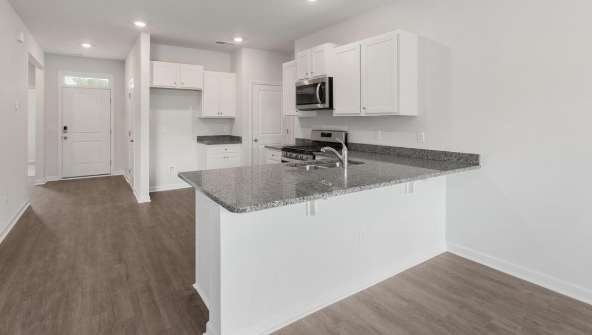 The open-concept layout begins with a welcoming foyer that leads into a spacious kitchen featuring a pantry and a convenient breakfast bar. The kitchen overlooks the living room, creating a bright, connected space.