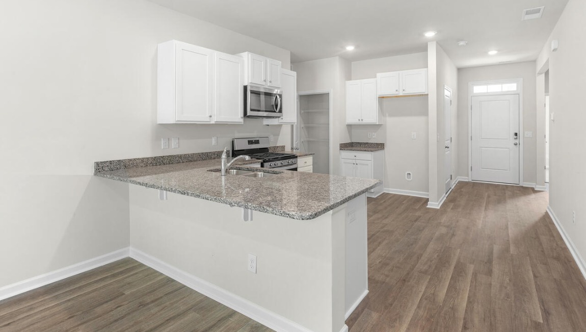 The open-concept layout begins with a welcoming foyer that leads into a spacious kitchen featuring a pantry and a convenient breakfast bar. The kitchen overlooks the living room, creating a bright, connected space.