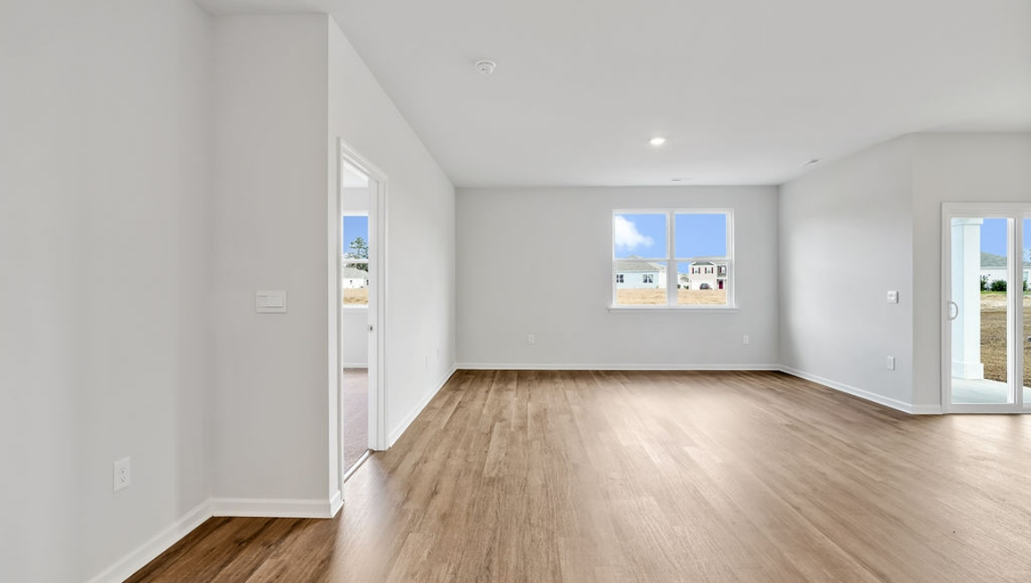 The open-concept family room, kitchen, and dining area feature granite countertops, stainless steel appliances, including a smooth-top range, dishwasher, and overhead microwave.