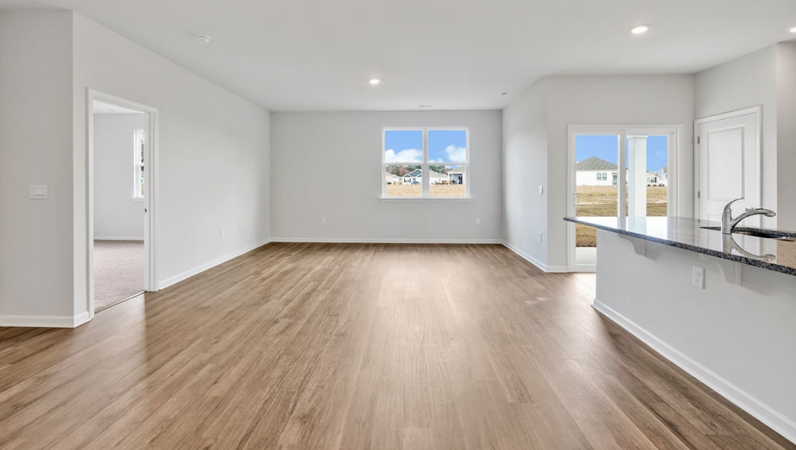 The open-concept family room, kitchen, and dining area feature granite countertops, stainless steel appliances, including a smooth-top range, dishwasher, and overhead microwave.