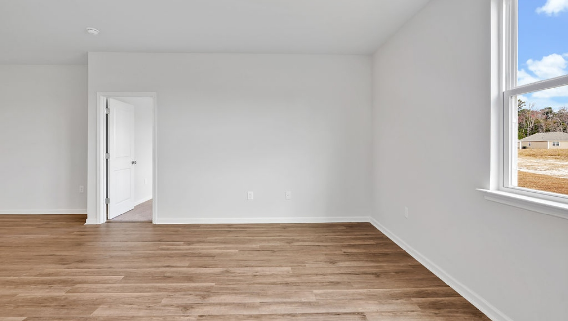 The open-concept family room, kitchen, and dining area feature granite countertops, stainless steel appliances, including a smooth-top range, dishwasher, and overhead microwave.