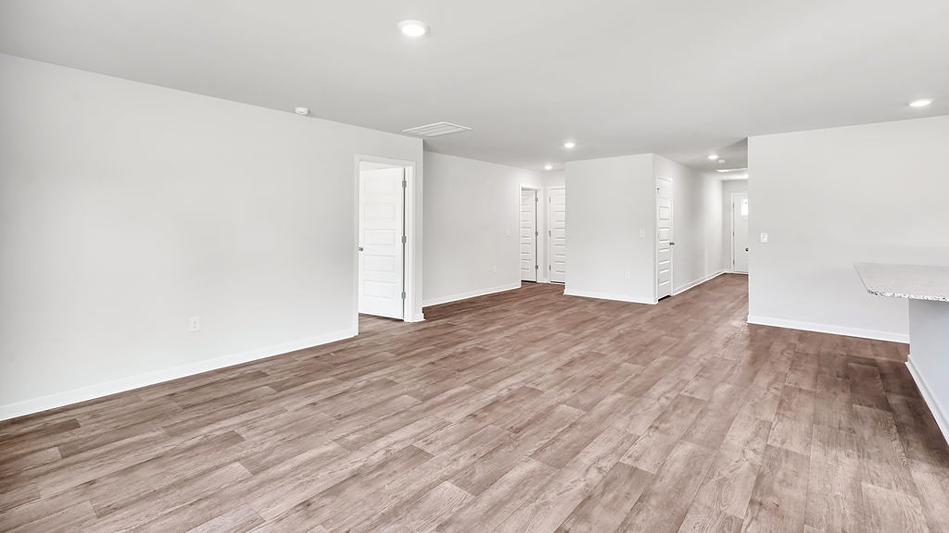 The open-concept family room, kitchen, and dining area feature granite countertops, stainless steel appliances, including a smooth-top range, dishwasher, and overhead microwave.