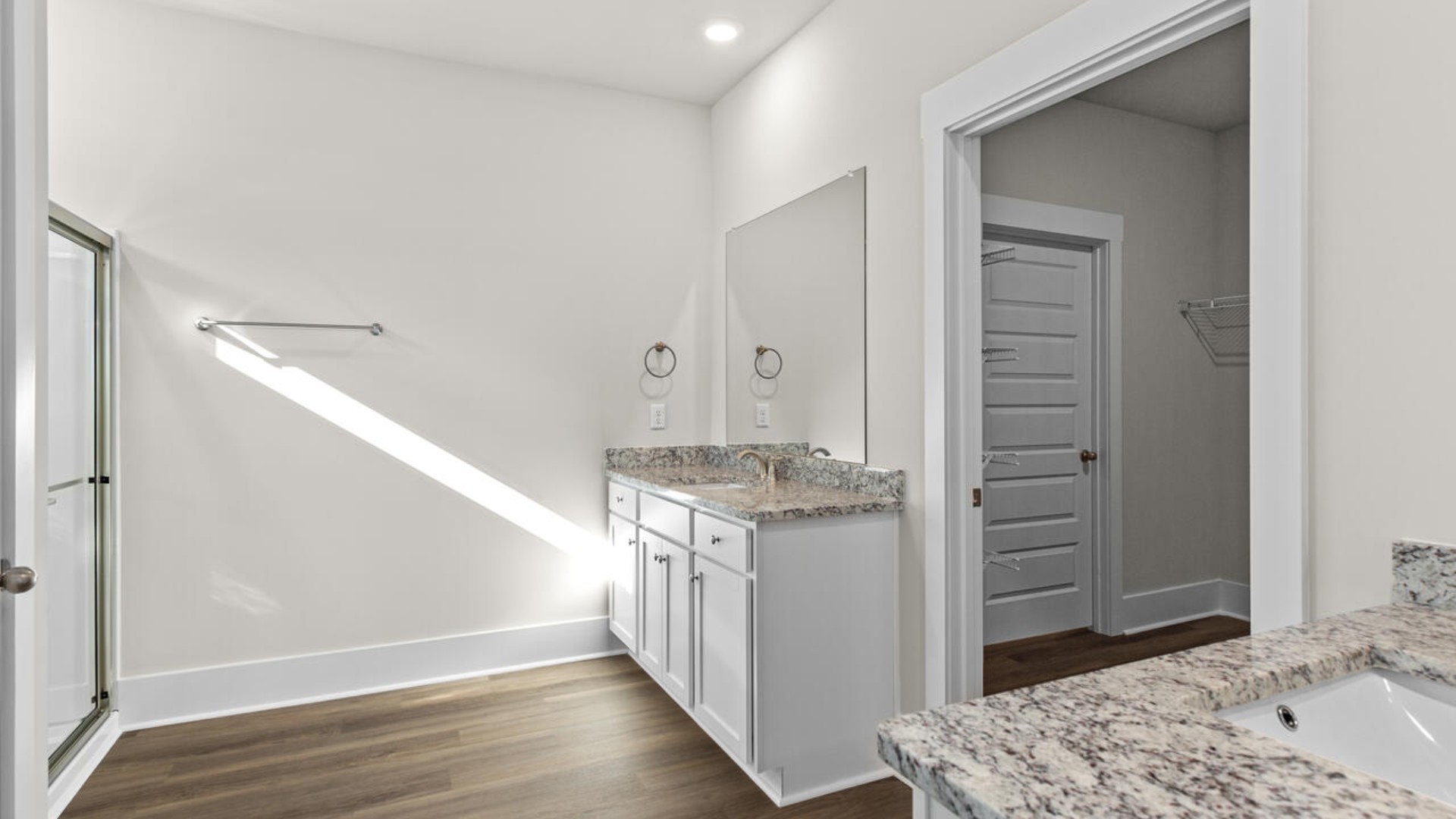 A large primary suite with bath that features separate sinks, granite countertops and a large walk-in closet.