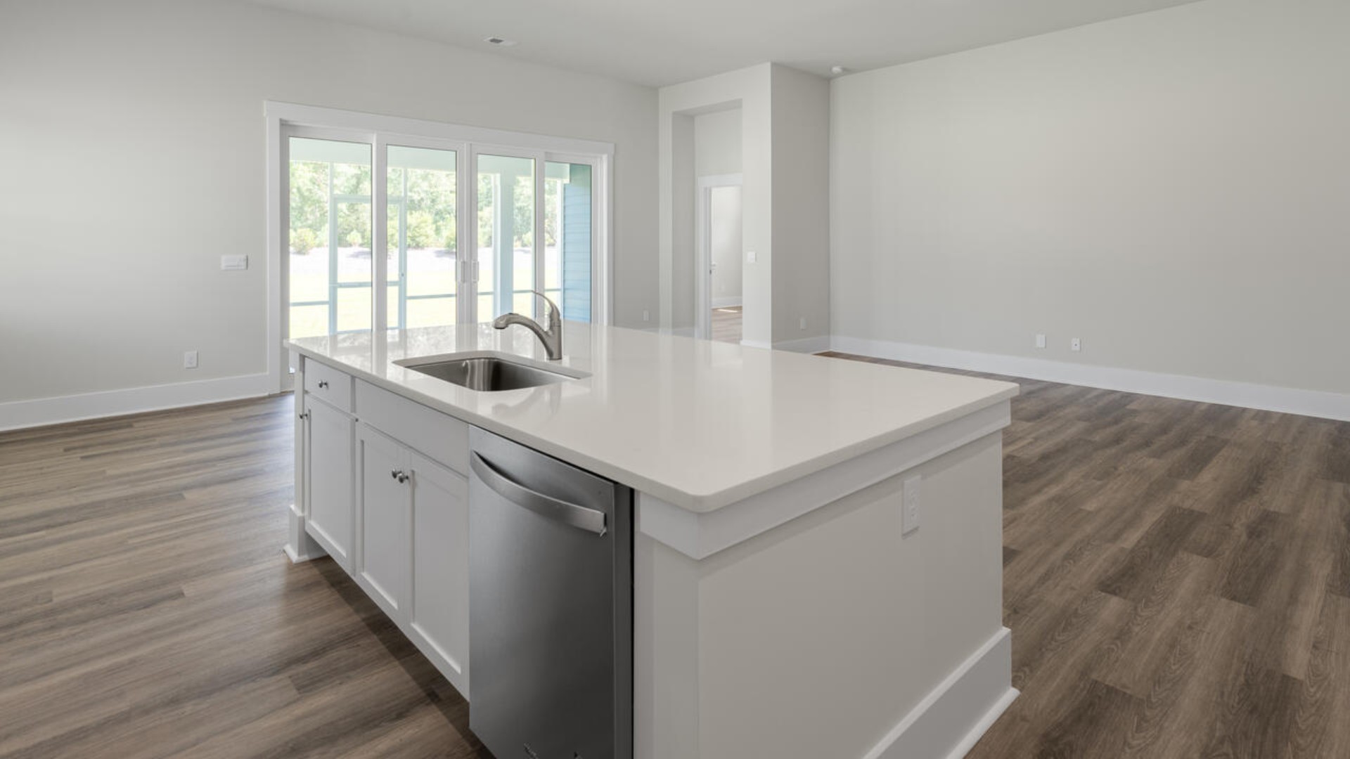 A large gourmet kitchen that features a large island, granite countertops, walk-in pantry, and stainless-steel appliances. Luxury Vinyl Plank flooring is included throughout the home