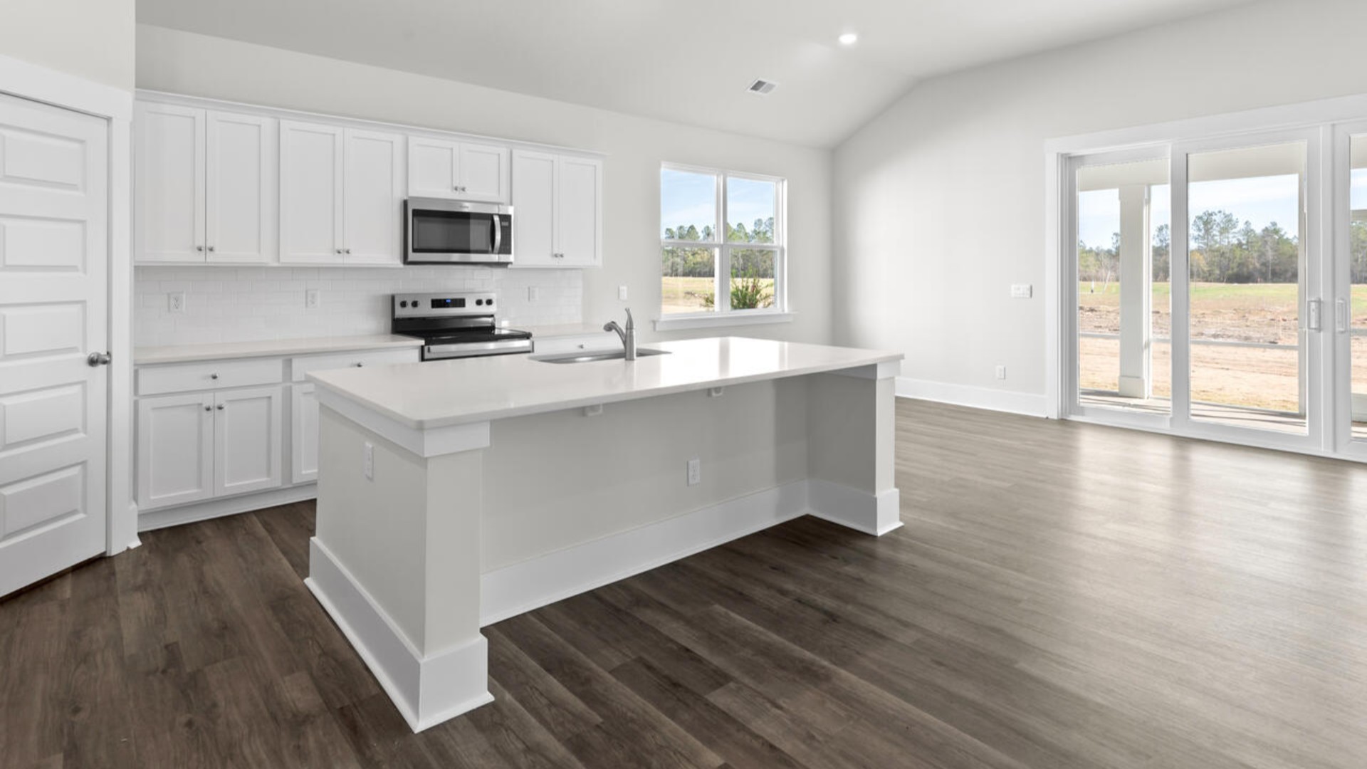 A large gourmet kitchen that features a large island, quartz countertops, walk-in pantry, and stainless-steel appliances. Luxury Vinyl Plank flooring is included throughout the home, giving you a wood-like look with the durability to handle all your beach days