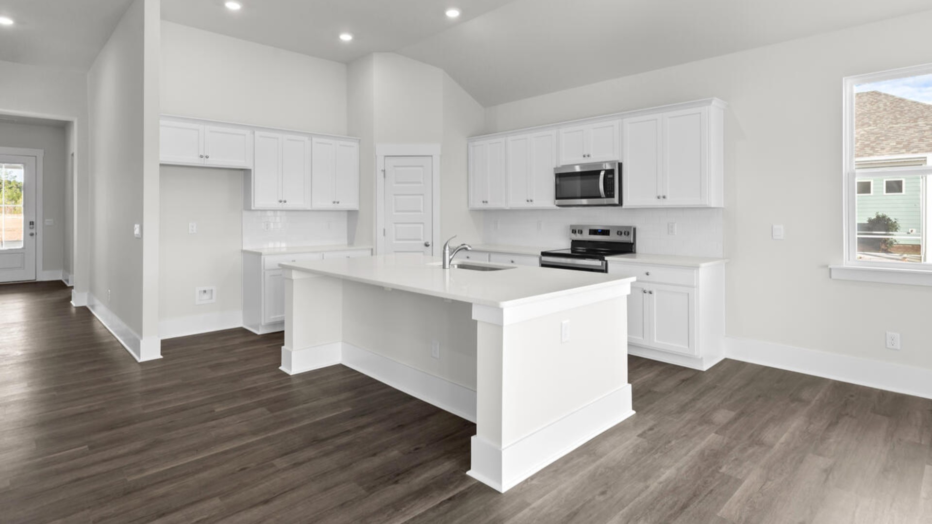 A large gourmet kitchen that features a large island, quartz countertops, walk-in pantry, and stainless-steel appliances. Luxury Vinyl Plank flooring is included throughout the home, giving you a wood-like look with the durability to handle all your beach days