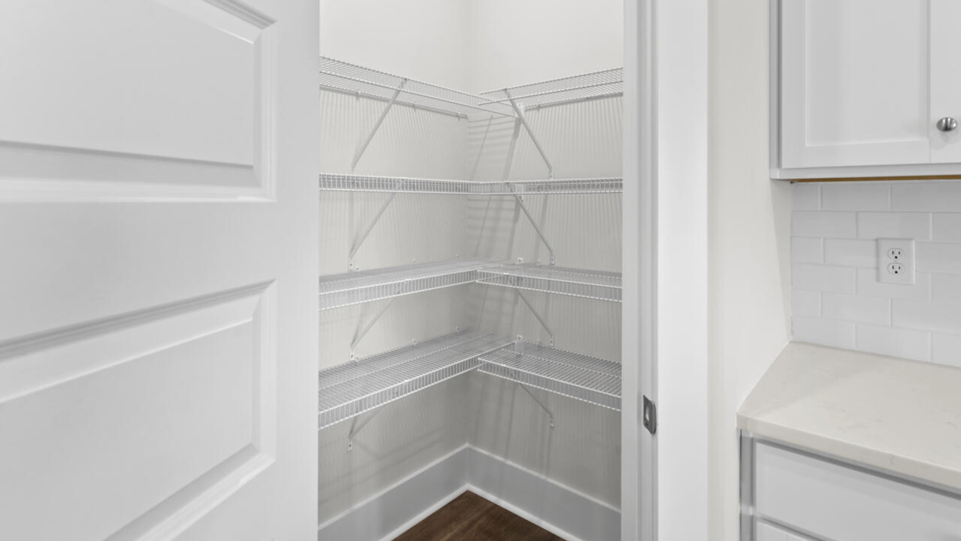 A large gourmet kitchen that features a large island, quartz countertops, walk-in pantry, and stainless-steel appliances. Luxury Vinyl Plank flooring is included throughout the home, giving you a wood-like look with the durability to handle all your beach days