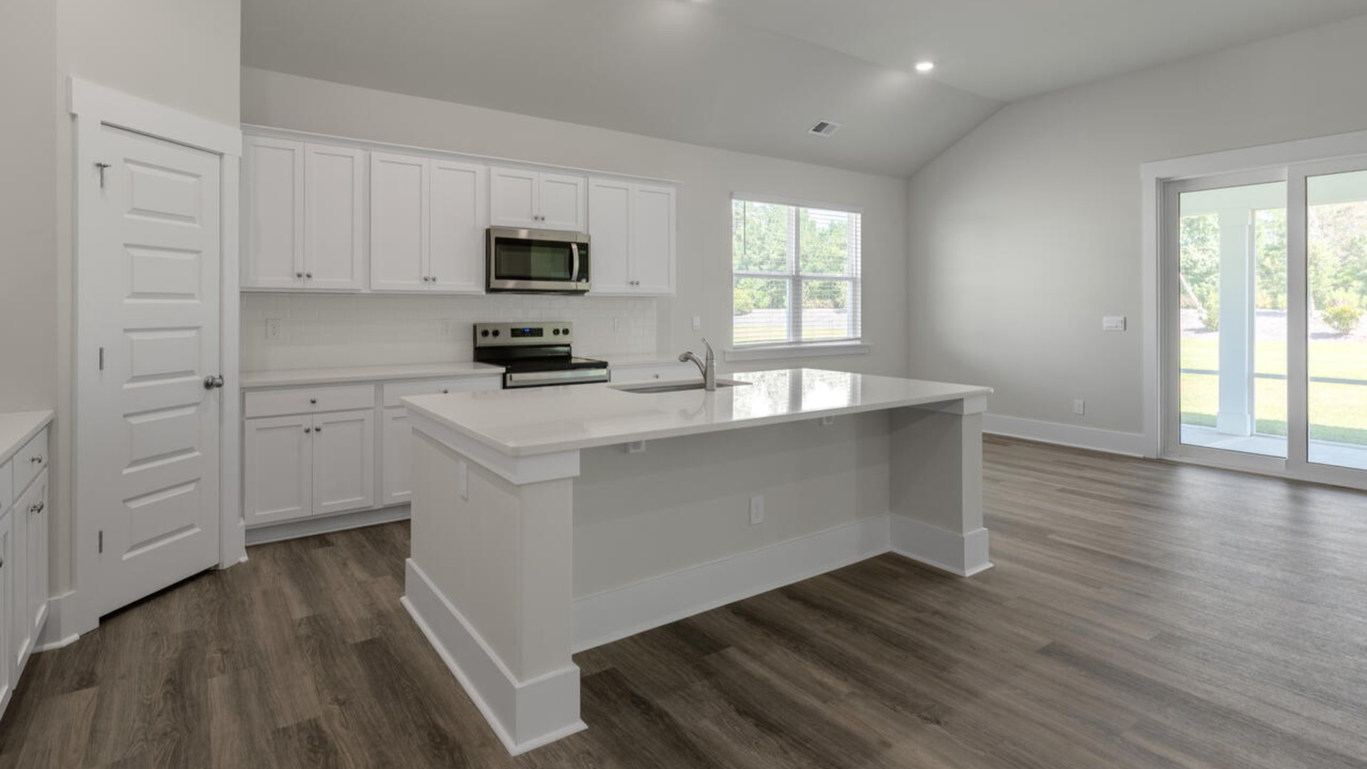 A large gourmet kitchen that features a large island, granite countertops, walk-in pantry, and stainless-steel appliances. Luxury Vinyl Plank flooring is included throughout the home, giving you a wood-like look with the durability to handle all your beach days