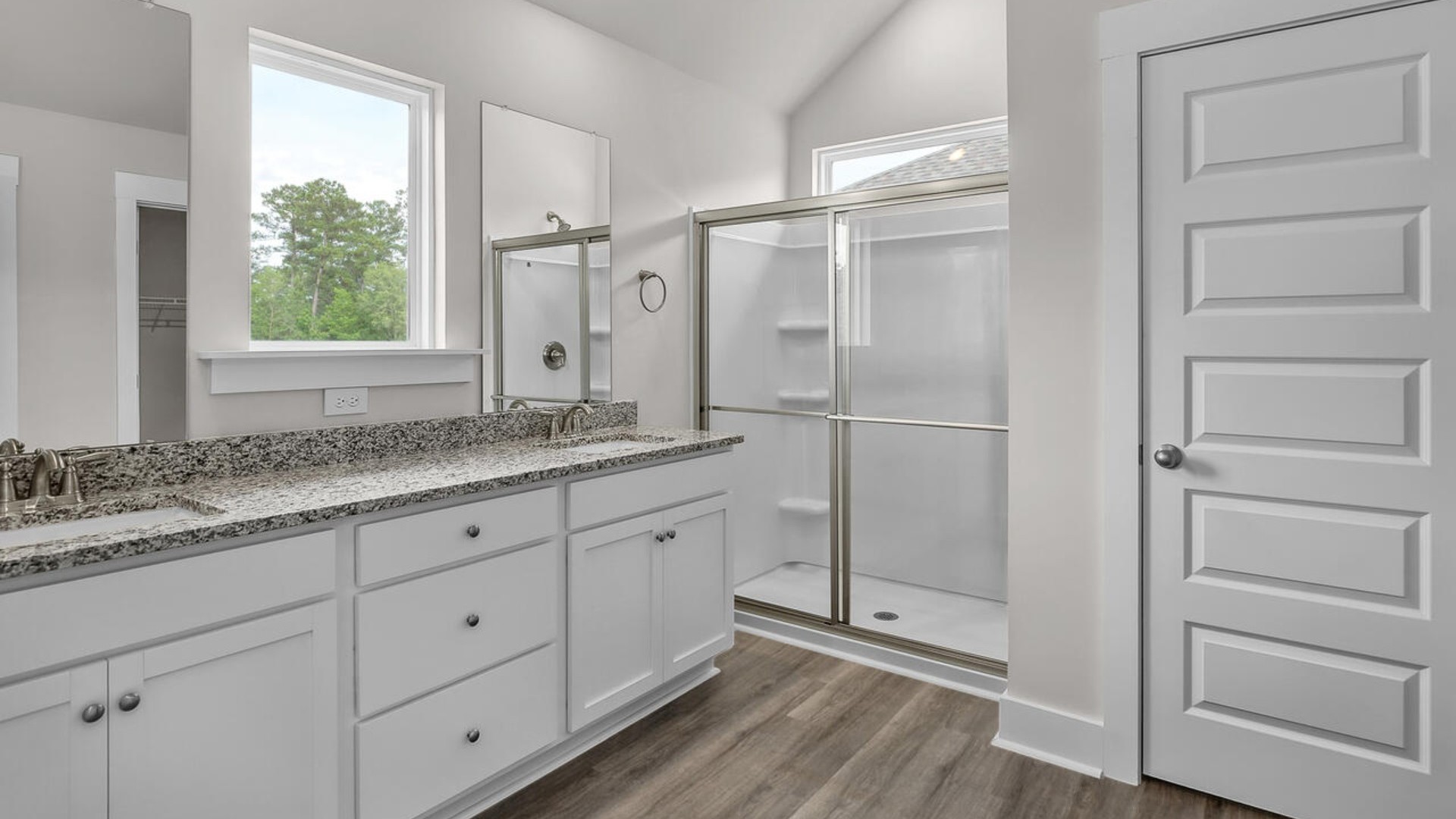 The primary suite features a sitting room, walk-in closet, trayed ceiling, a step-in 5-foot shower, dual vanity with granite countertops, and natural light in the bathroom.