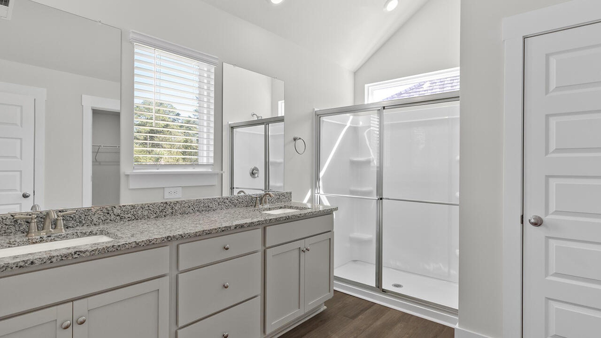 The primary suite features a sitting room, walk-in closet, trayed ceiling, a step-in 5-foot shower, dual vanity with granite countertops, and natural light in the bathroom.