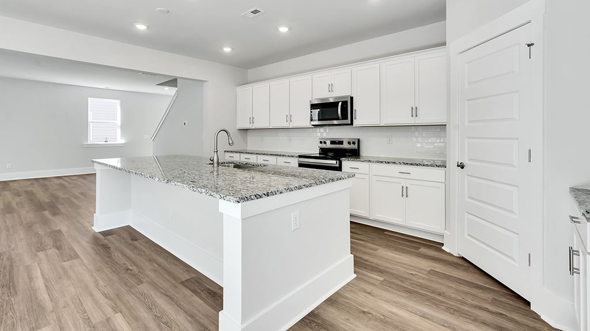 The gourmet kitchen serves as the focal point, anchored by a grand center island with seating, a walk-in pantry, and a seamless flow into the living room—complete with an optional fireplace.