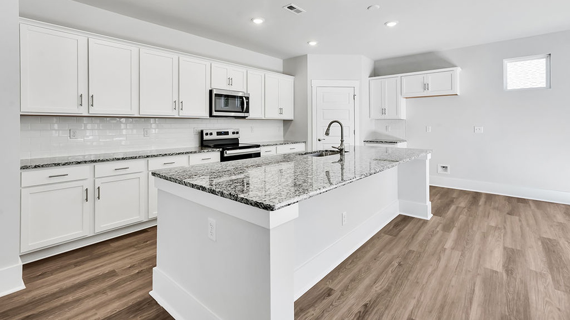 The gourmet kitchen serves as the focal point, anchored by a grand center island with seating, a walk-in pantry, and a seamless flow into the living room—complete with an optional fireplace.
