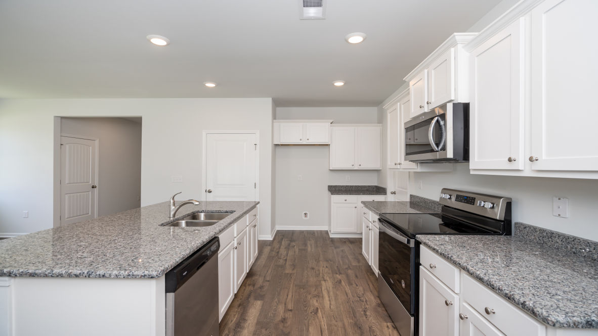 This new home kitchen features Stainless Steel Appliances, granite countertops and smooth-top electric range, microwave and dishwasher. Plenty of cabinet space.