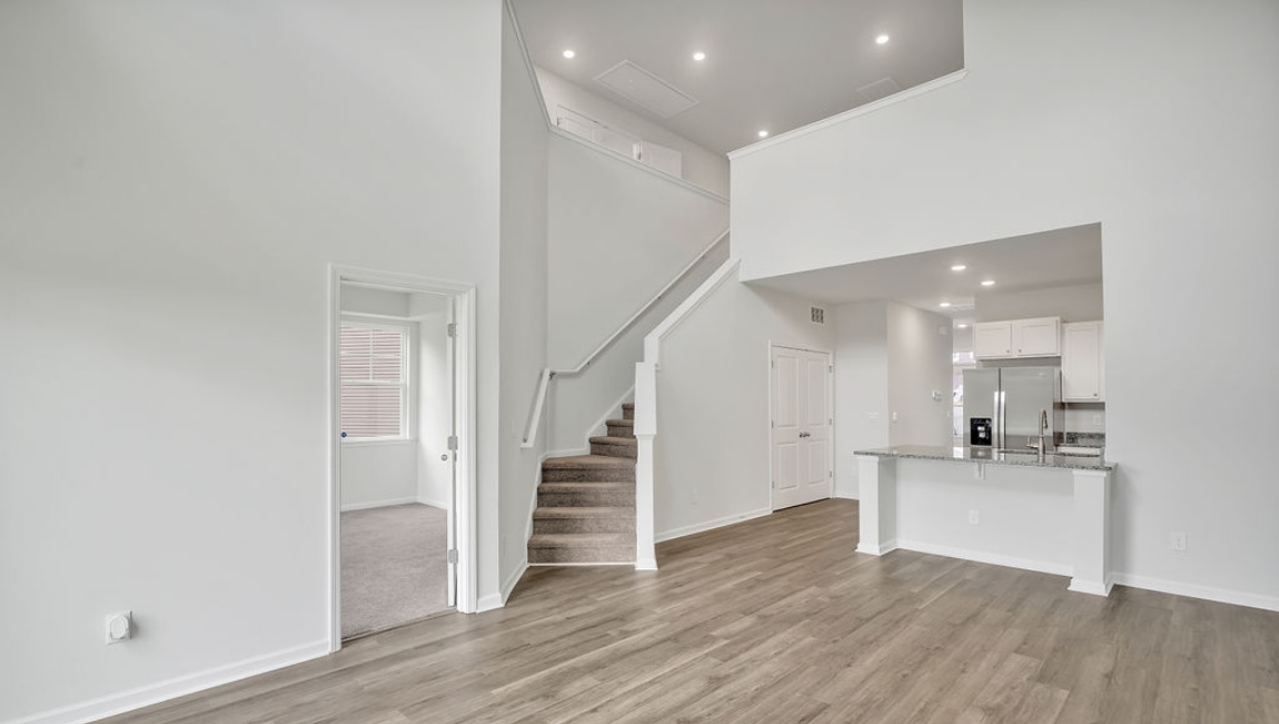The open concept living room off the kitchen offers a feeling of grandeur with it's two-story ceilings and so much natural light to take in nature overlooking the pond.