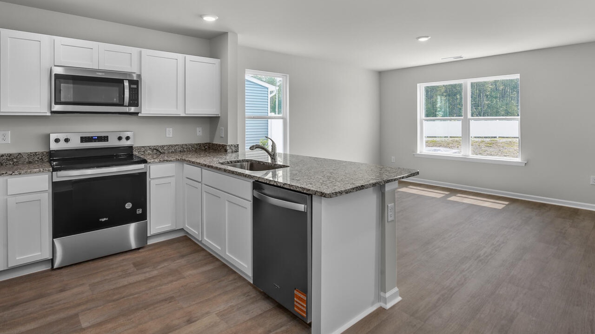 The kitchen overlooks the dining and living spaces, ideal for entertaining guests or enjoying family time while preparing meals with new stainless-steel appliances and granite countertops.