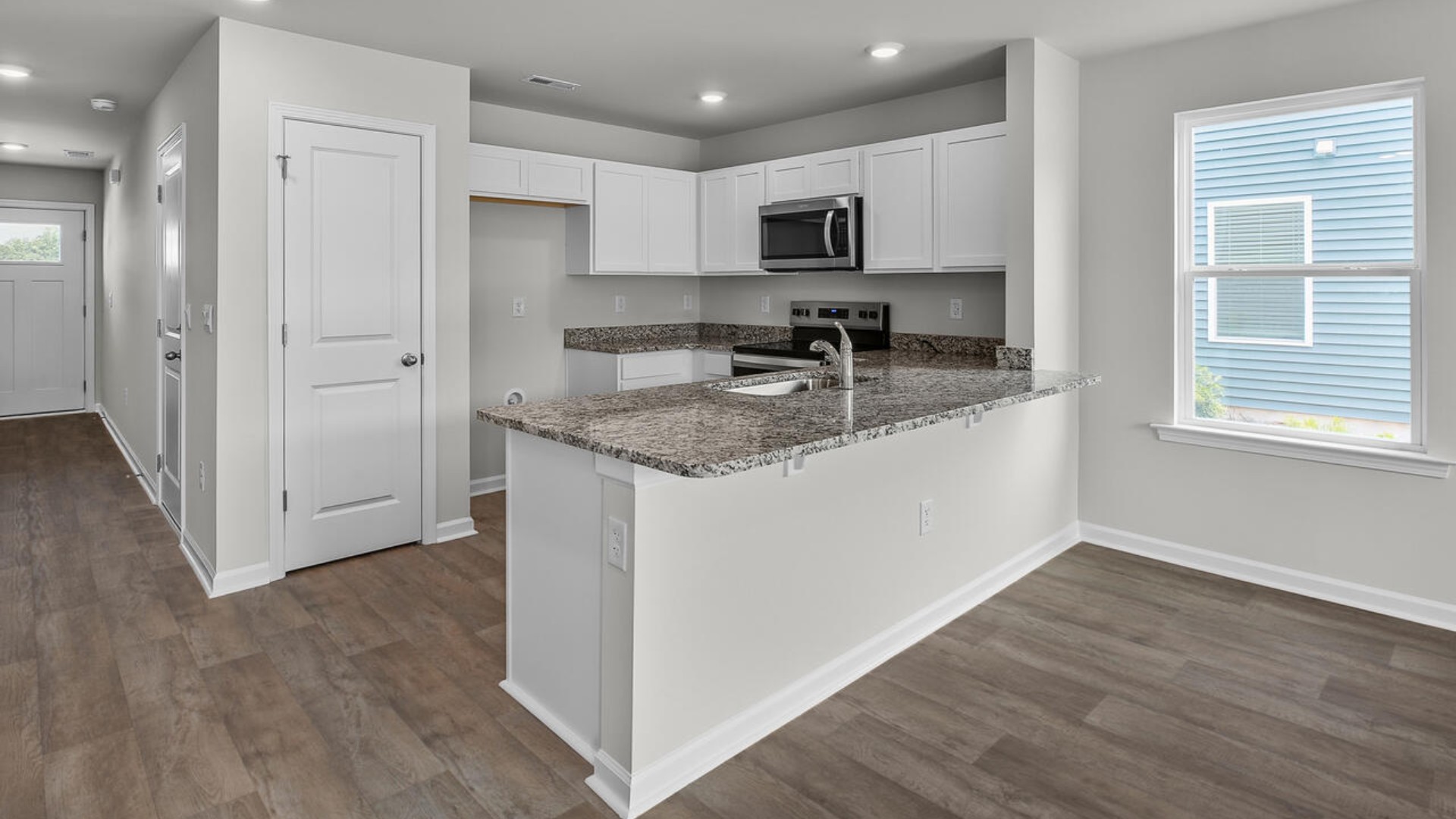 The kitchen overlooks the dining and living spaces, ideal for entertaining guests or enjoying family time while preparing meals with new stainless-steel appliances and granite countertops.
