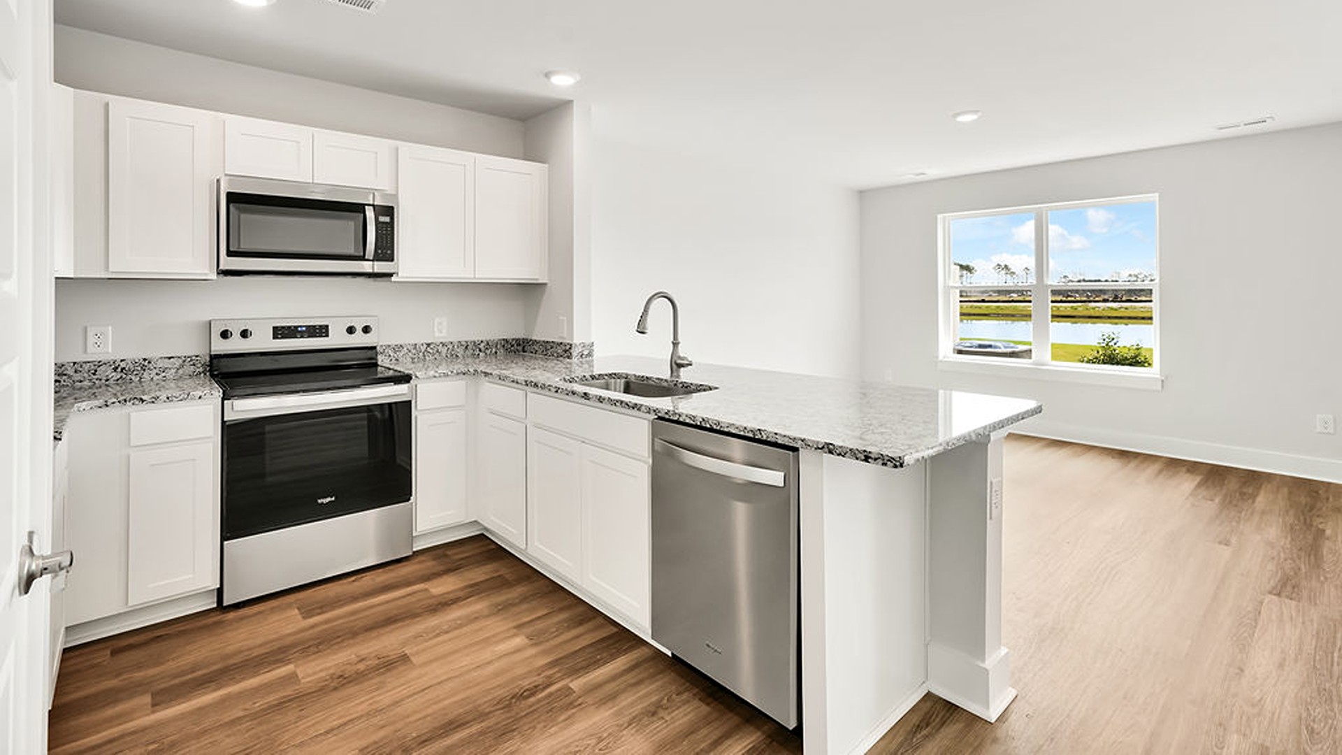 The kitchen overlooks the dining and living spaces, ideal for entertaining guests or enjoying family time while preparing meals with new stainless-steel appliances and granite countertops.