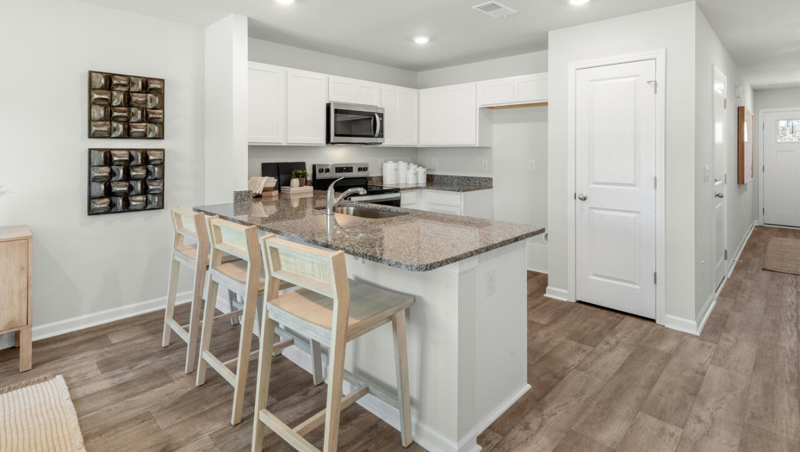 The kitchen overlooks the dining and living spaces, ideal for entertaining guests or enjoying family time while preparing meals with new stainless-steel appliances and granite countertops.
