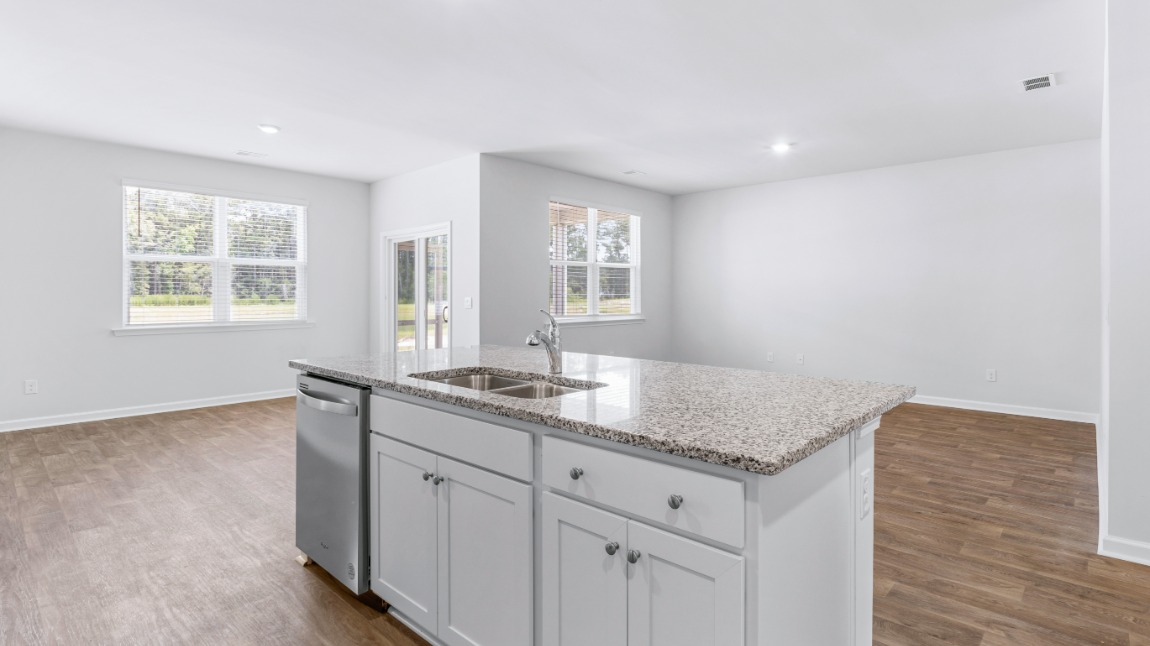 The kitchen includes a walk-in pantry, stainless-steel appliances, and a large island for bar seating. Enjoy a meal with family and friends in the dining area that allows access to the covered back porch.