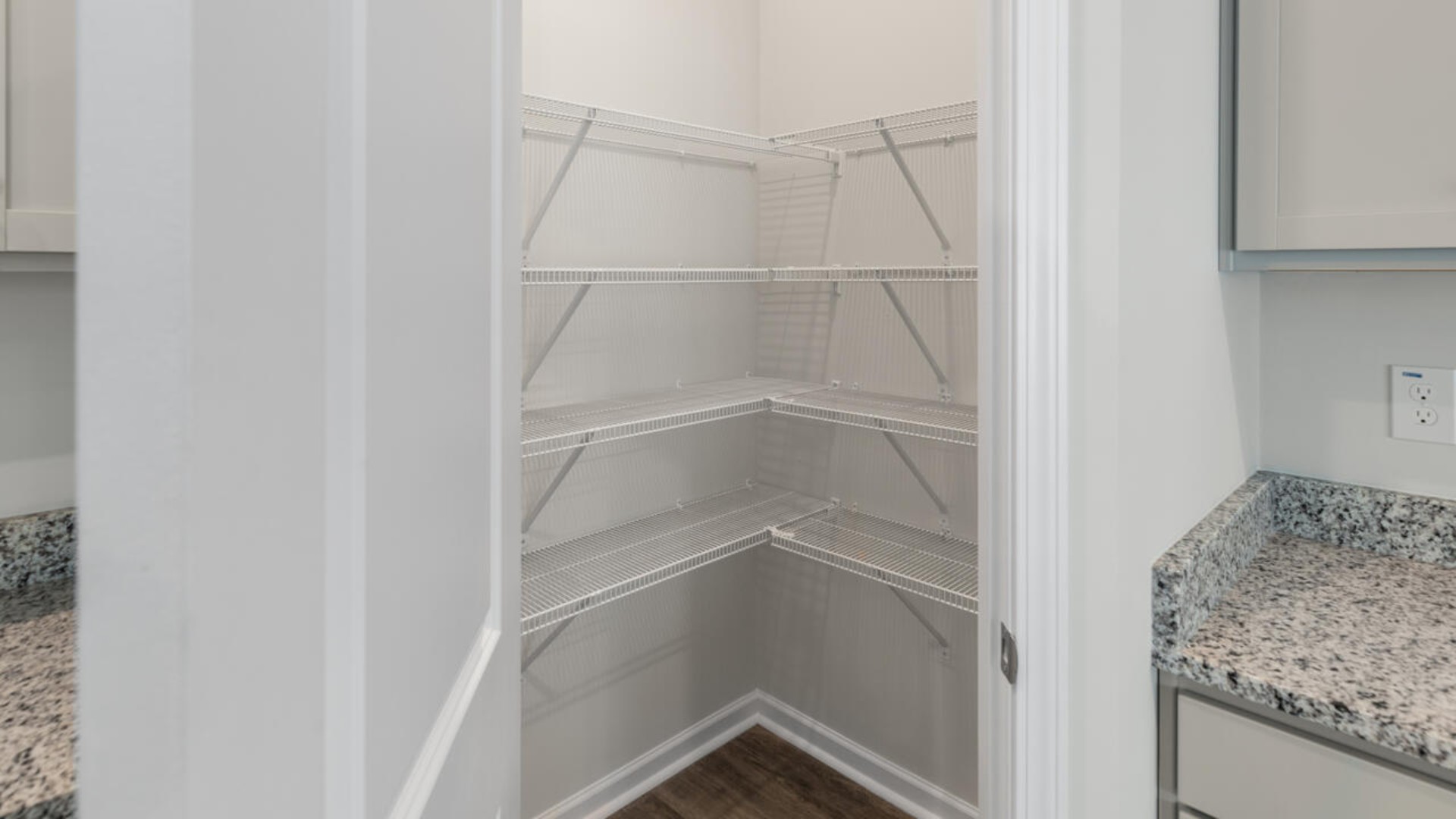 A large gourmet kitchen that features a large island, granite countertops, walk-in pantry, and stainless-steel appliances. Luxury Vinyl Plank flooring is included throughout the home, giving you a wood-like look with the durability to handle all your beach days