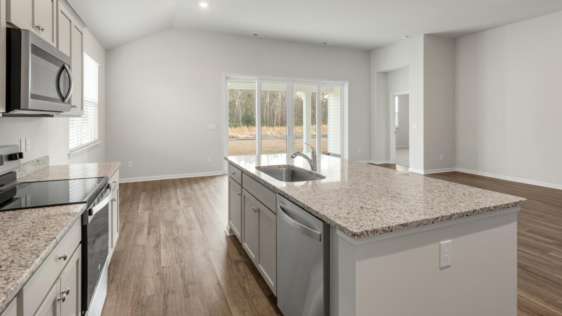 A large gourmet kitchen that features a large island, granite countertops, walk-in pantry, and stainless-steel appliances. Luxury Vinyl Plank flooring is included throughout the home, giving you a wood-like look with the durability to handle all your beach days