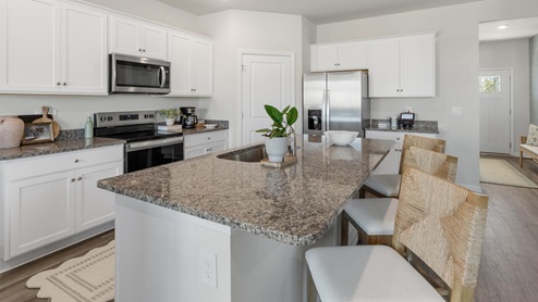 The main level features a flex room adjacent to the foyer, ideal for a formal dining room or home office. The gourmet kitchen has an oversized island for extra seating and a large pantry, and it opens to the dining area and a spacious living room. A bedroom with a full bathroom completes the main level.