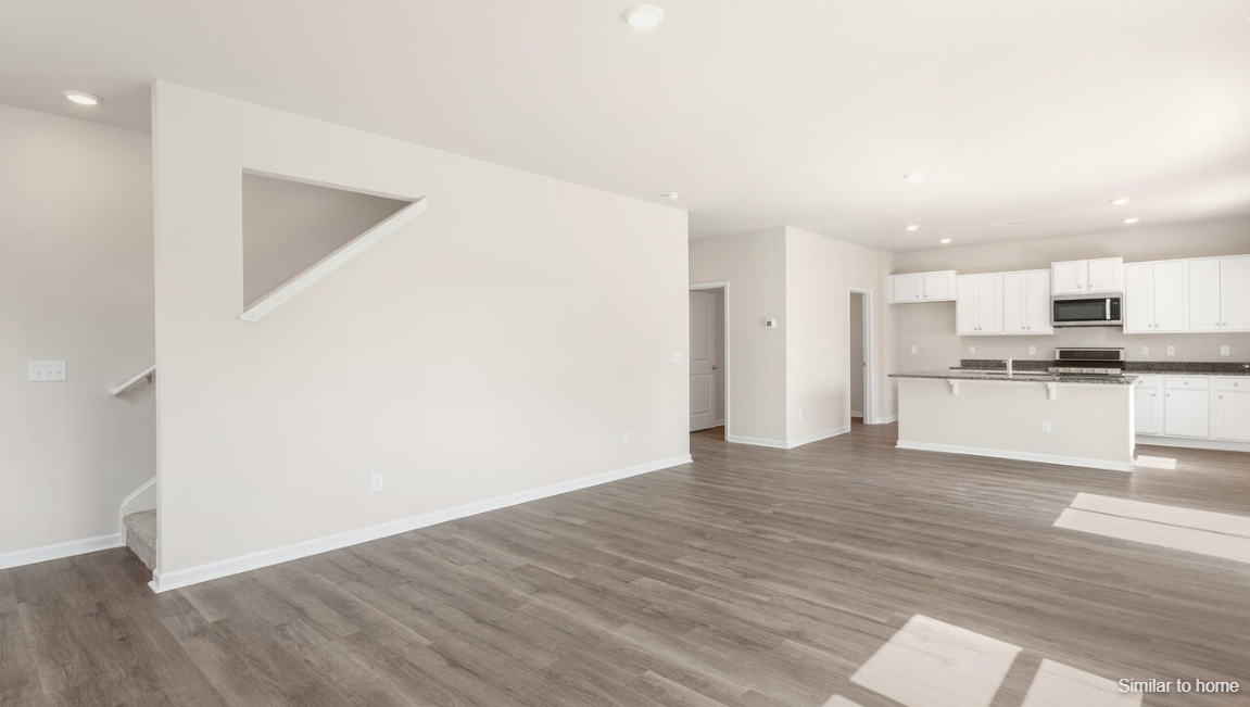 Its open-concept design includes a kitchen with granite countertops and stainless steel appliances, an island, and a walk-in pantry,