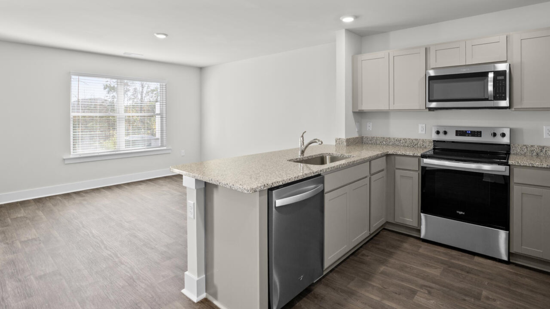 The kitchen overlooks the dining and living spaces, ideal for entertaining guests or enjoying family time while preparing meals with new stainless-steel appliances and granite countertops.