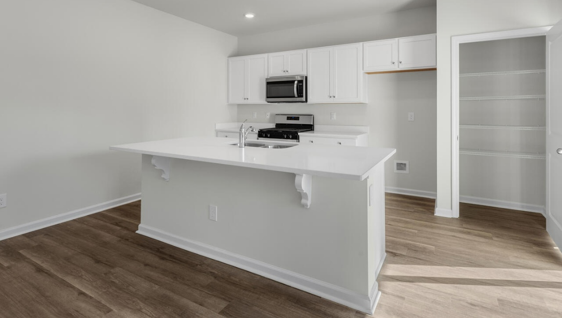 New Homes in Leland NC. The Kerry floor plan offers open living space and a 2-car garage. At the front are two guest bedrooms and a full bathroom, perfect for visitors or a home office. The open-concept family room, kitchen, and dining area feature Granite countertops, stainless steel appliances, including a smooth-top range, dishwasher and overhead microwave