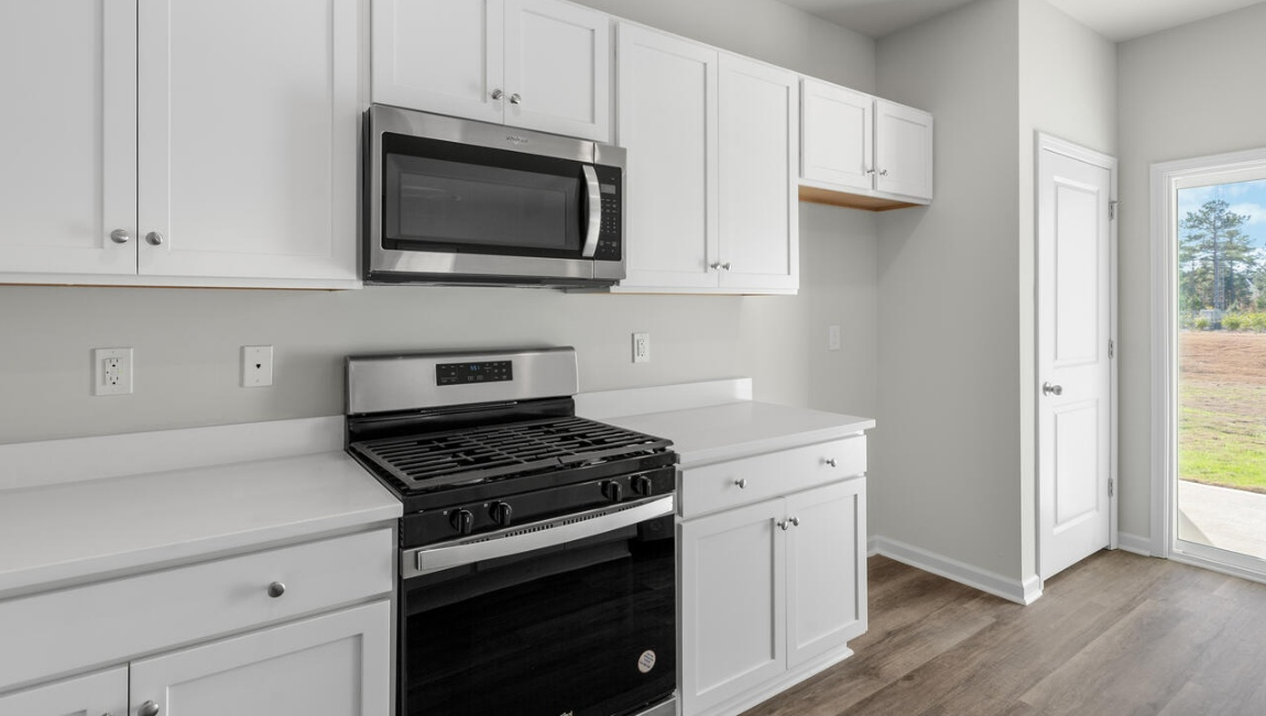 New Homes in Leland NC. The Kerry floor plan offers open living space and a 2-car garage. At the front are two guest bedrooms and a full bathroom, perfect for visitors or a home office. The open-concept family room, kitchen, and dining area feature Granite countertops, stainless steel appliances, including a smooth-top range, dishwasher and overhead microwave