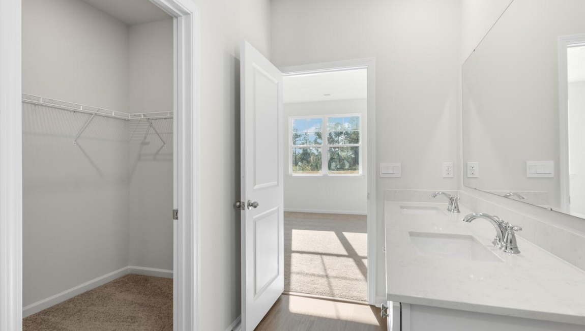 New Homes in Leland NC. The Kerry floor plan offers open living space and a 2-car garage. At the front are two guest bedrooms and a full bathroom, perfect for visitors or a home office. The open-concept family room, kitchen, and dining area feature Granite countertops, stainless steel appliances, including a smooth-top range, dishwasher and overhead microwave