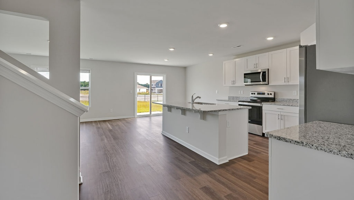 New Homes in Leland NC. The Hayden Floorplan offers 2,511 square feet with 5 bedrooms, 3 full bathrooms, and a 2-car garage. The upstairs has an additional living space, a laundry room, and a Primary Bedroom. Downstairs, a flex room can be used as an office or sitting area, while the open-concept kitchen features granite countertops and stainless steel appliances.