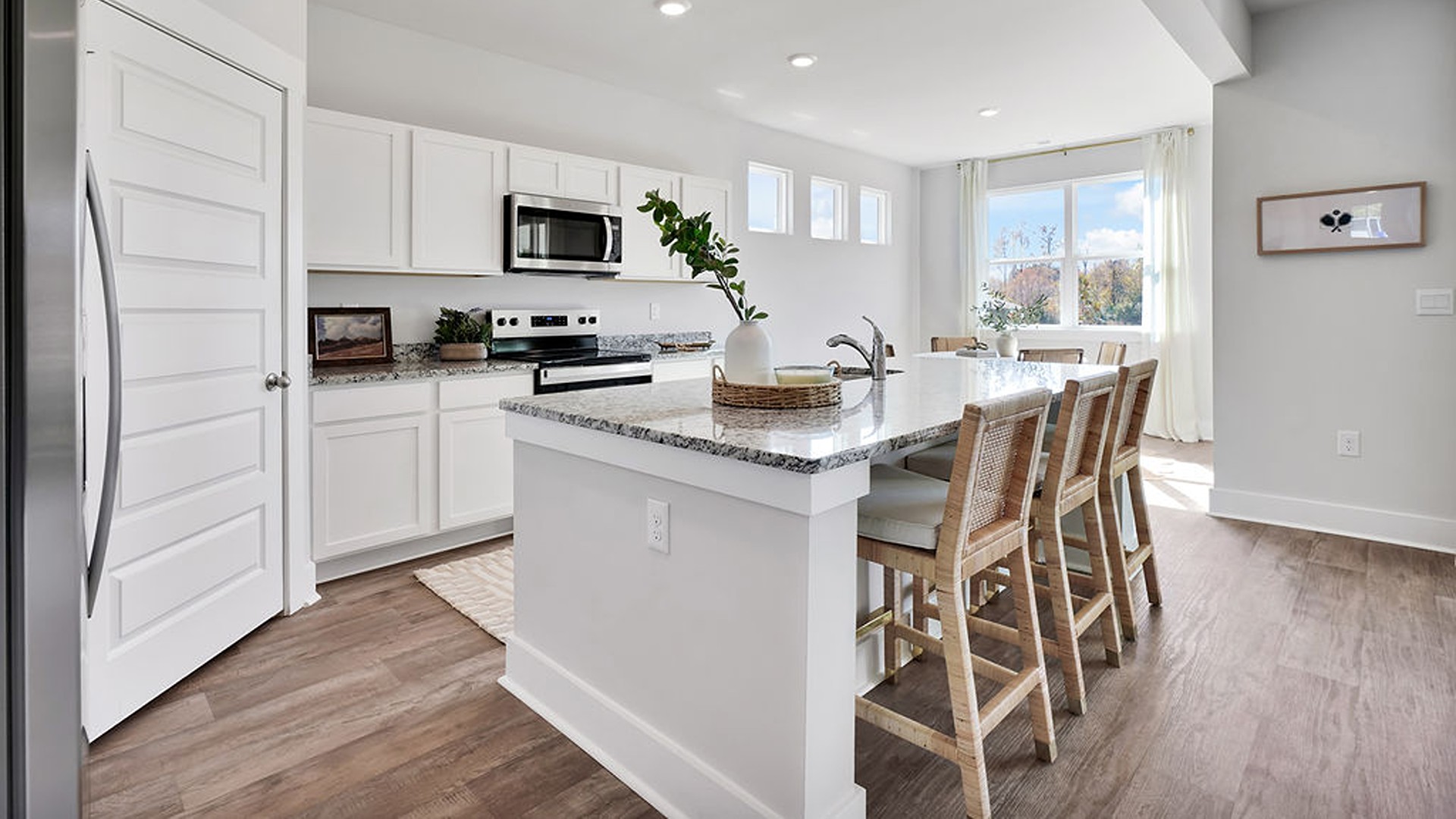 The kitchen boasts stainless steel appliances, a walk-in pantry, and a generous island that flows seamlessly into the main living area. Durable luxury vinyl plank flooring runs throughout the first floor, designed to handle your beach days year-round.
