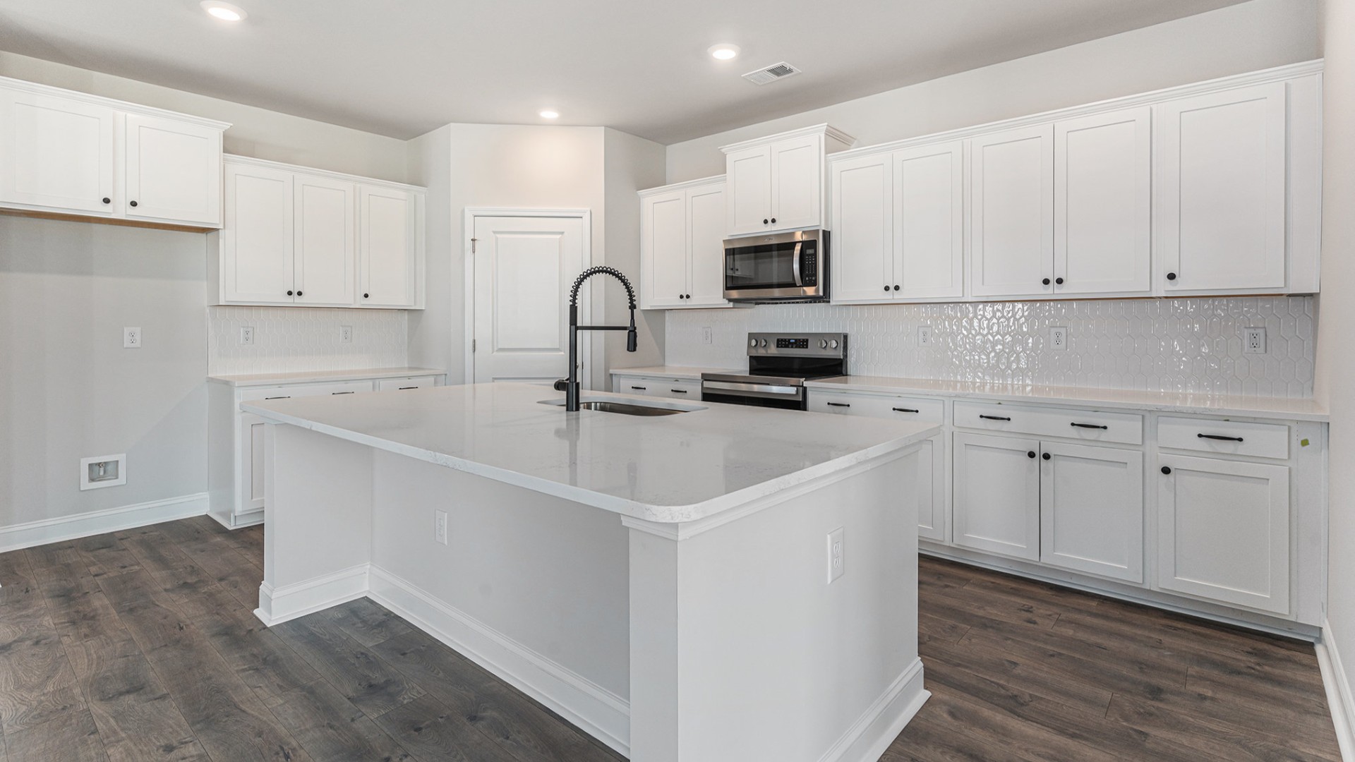 The open-concept kitchen shines with granite countertops, a stylish tile backsplash, a large island, and LVP flooring that extends through the main living areas.