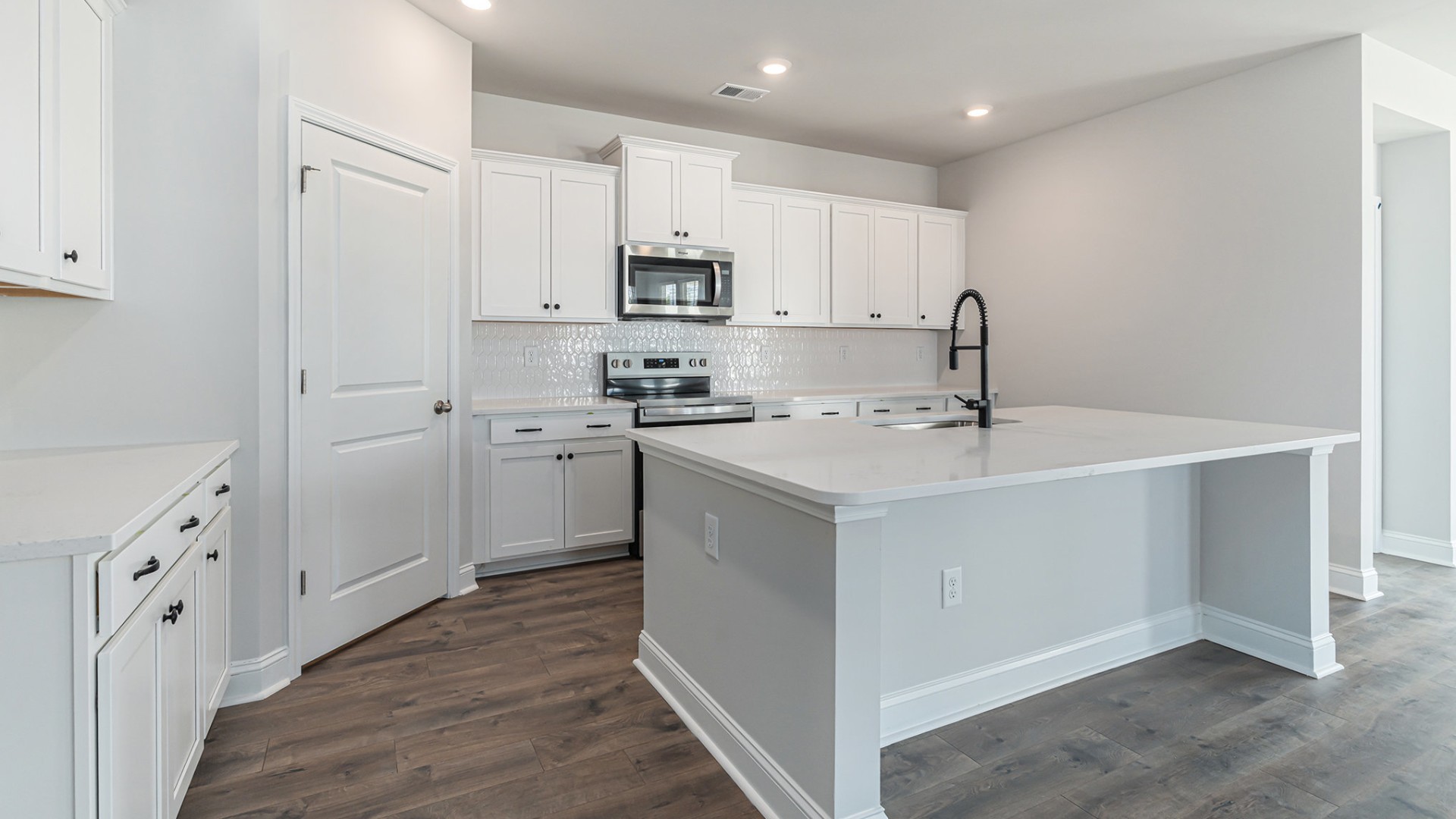The open-concept kitchen shines with granite countertops, a stylish tile backsplash, a large island, and LVP flooring that extends through the main living areas.